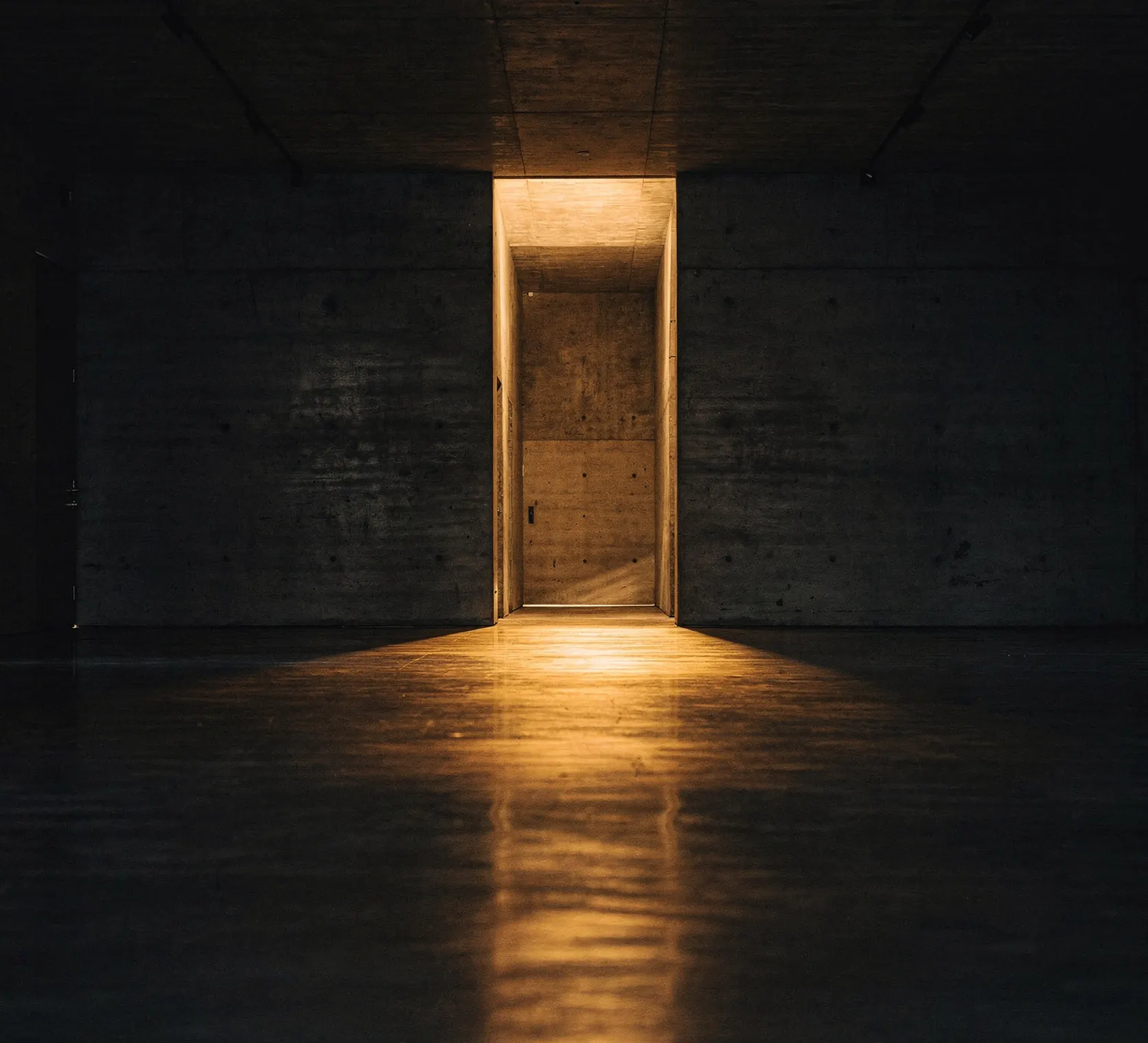 Corredor escuro com uma porta iluminada ao fundo